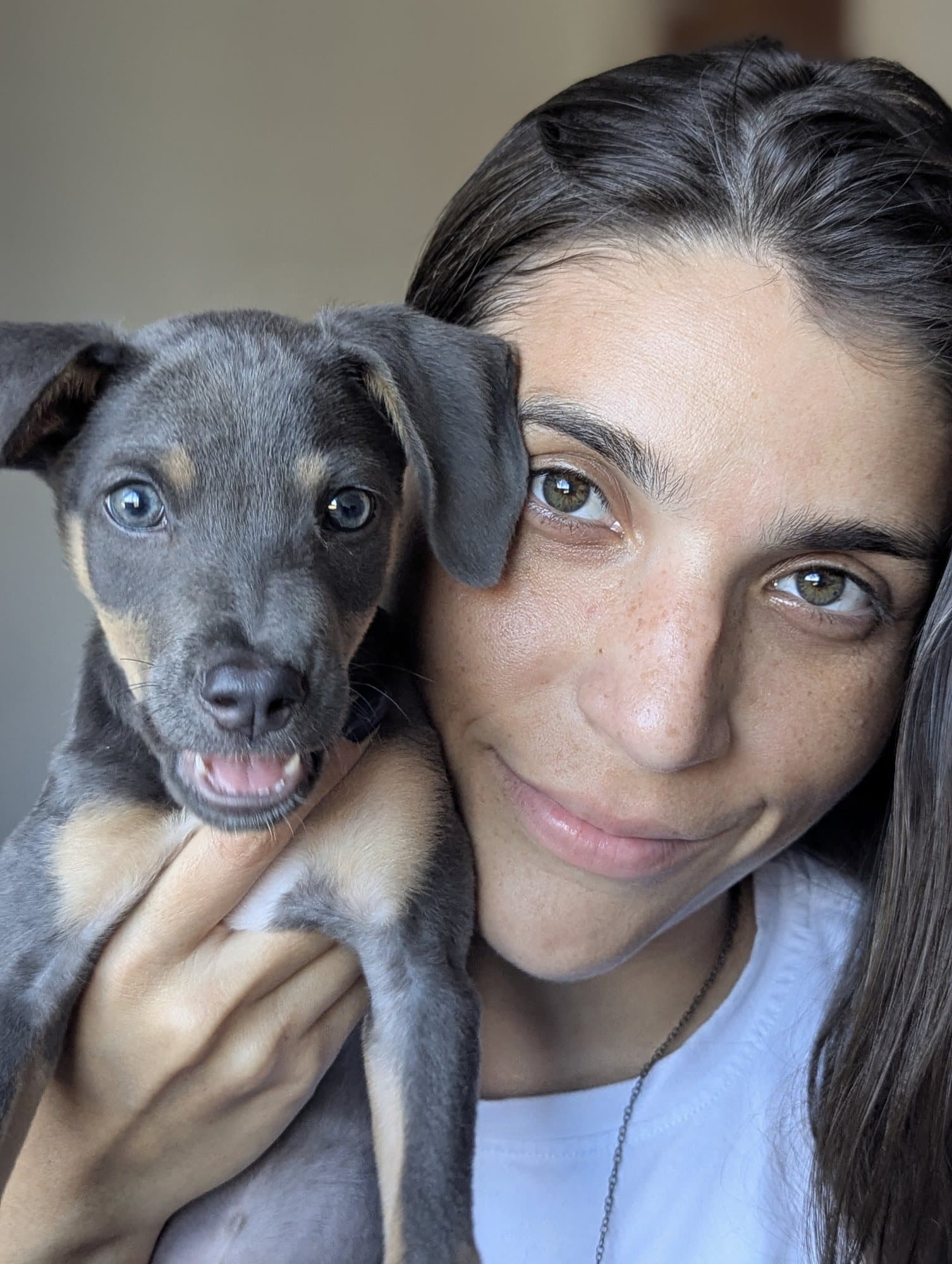 Val abrazando a una perrita cachorra gris