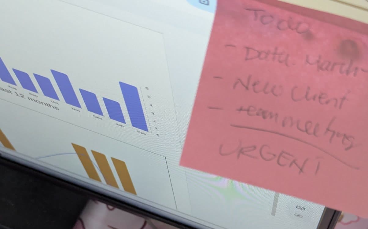 Post-it rosado de pendientes pegado junto a una pantalla con gráficos de barras